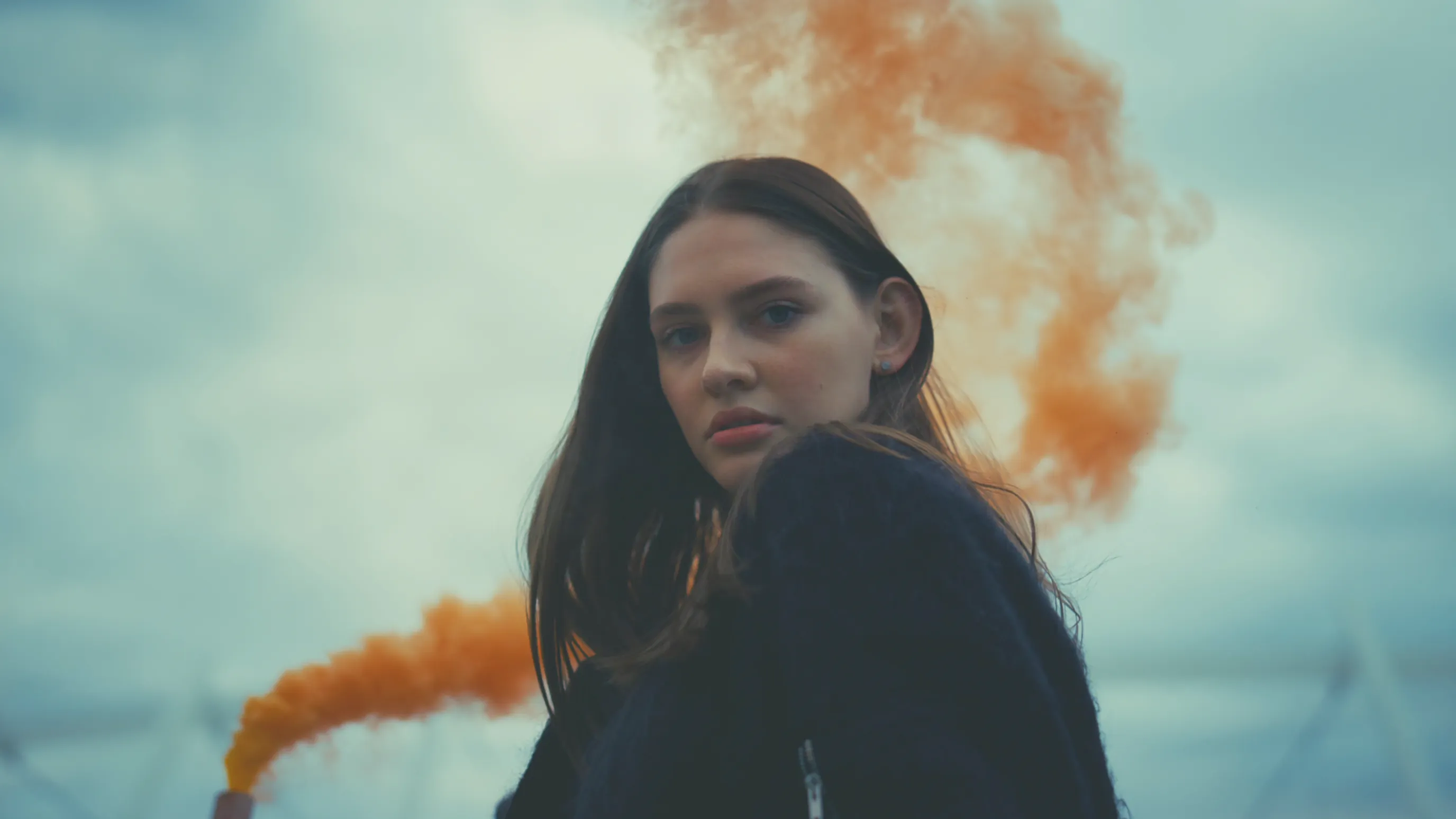 Woman in orange smoke with a vivid teal-and-orange cinematic color grade