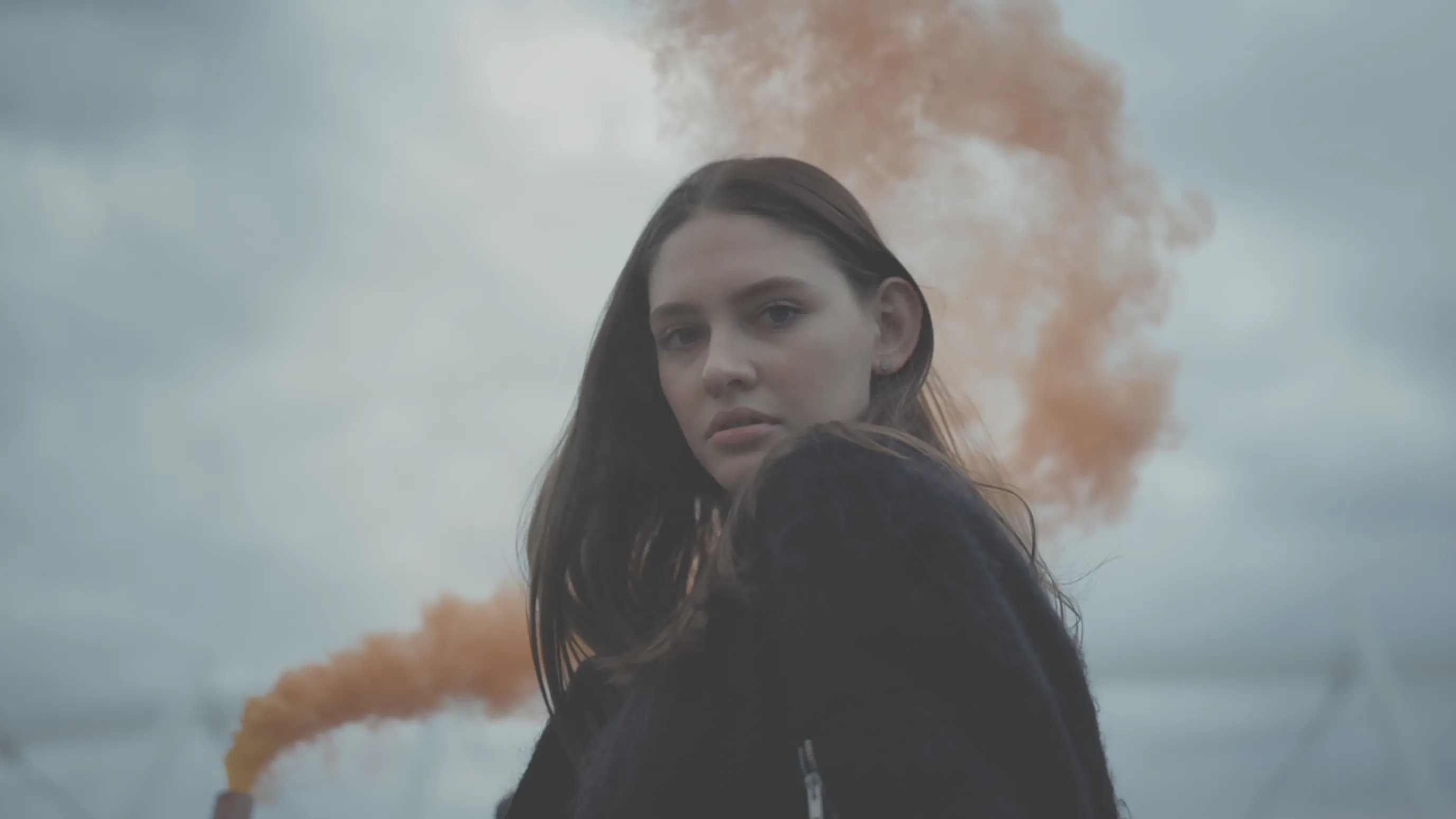Woman in orange smoke with a neutral, low-contrast color profile