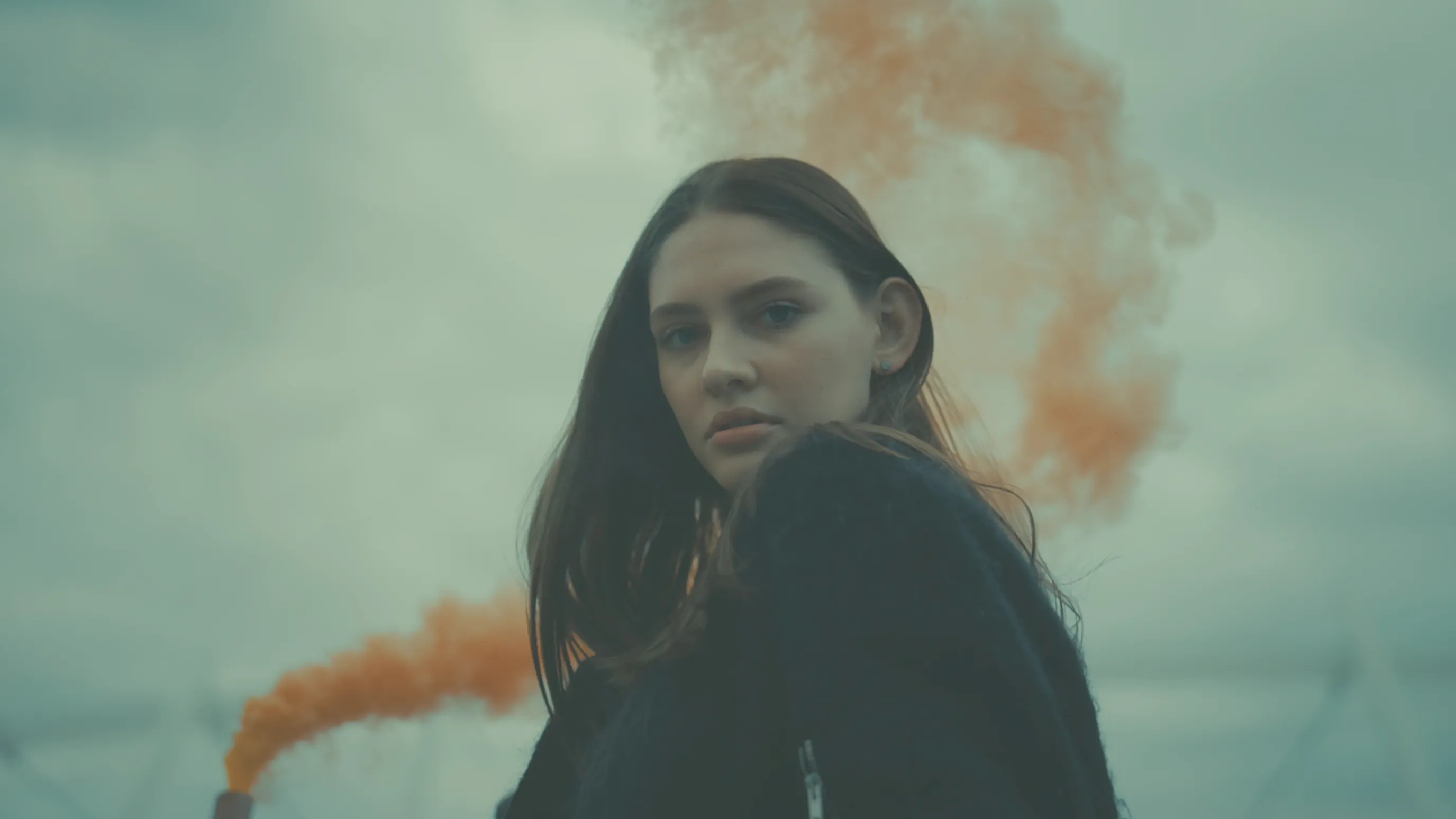Woman in orange smoke with a faded green vintage color grade
